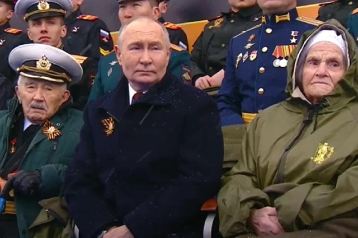 Ветераны Алешина и Куропатков смотрят парад Победы, сидя рядом с Путиным