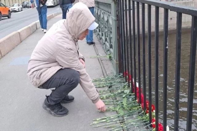 Люди несут цветы к месту трагедии.