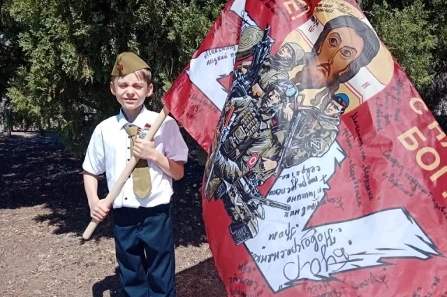 На этом флаге, который в руках у Максима, свои послания оставили бойцы СВО.