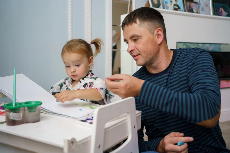 Есения показывает папе свои рисунки. 