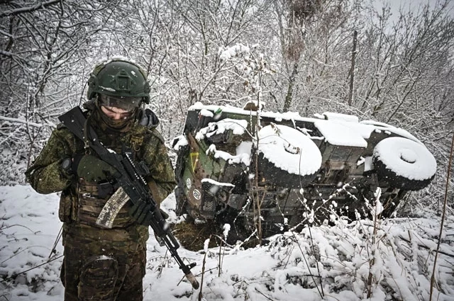 Российский военнослужащий возле подбитого бронеавтомобиля ВСУ