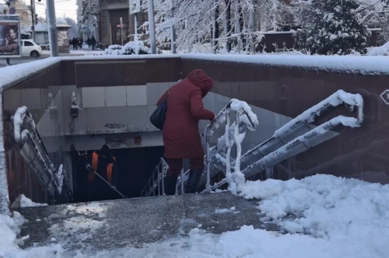 Прохожие держатся за поручни при спуске в подземный переход.