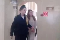 Маму мальчика ведут в зал суда.