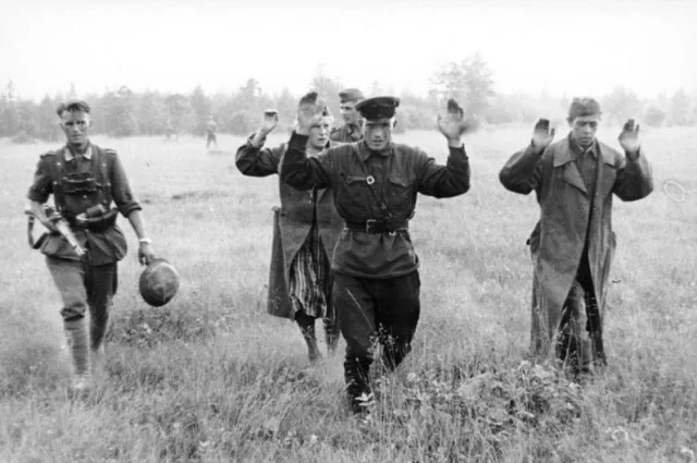 Немецкий военнослужащий в годы Великой Отечественной конвоирует сдавшихся советских солдат. В первые месяцы войны в плен попадало много бойцов, но вели они себя по-разному.