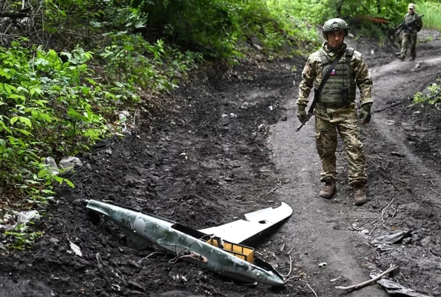 Российский военнослужащий стоит возле сбитого украинского БПЛА.