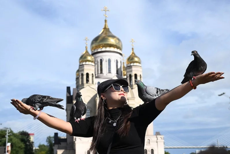 Туристка кормит голубей на площади Борцов Революции во Владивостоке.