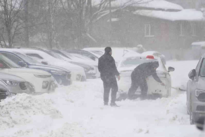 Водитель откапывает свой автомобиль из снега в Мытищах. 