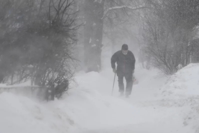 Мужчина во время снежной метели на улице в Мытищах. 