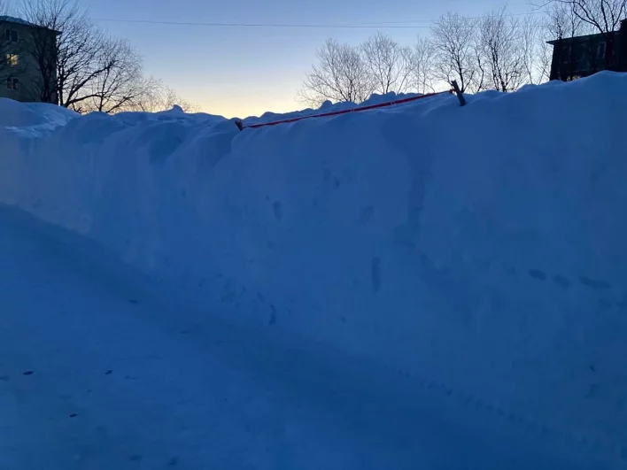 Автомобилисты после снегопадов отмечают местонахождение своих машин сигнальными лентами.