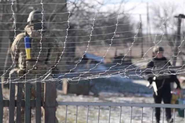 Сотрудники Национальной полиции Украины стоят возле сетки для защиты от беспилотников во время эвакуации жителей сел Таврийское и Юрковка в Запорожской области Украины.