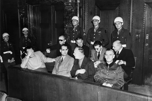 Нюрнбергский процесс. На скамье подсудимых военные преступники, привлечённые к суду Международного военного трибунала в Нюрнберге. В первом ряду слева направо: Герман Геринг, Рудольф Гесс, Иоахим фон Риббентроп, Вильгельм Кейтель. Во втором ряду: Карл Дениц, Эрих Редер, Бальдур фон Ширах, Фриц Заукельд.
