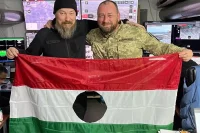 Шандор держит дырявый флаг вместе с командующим силами беспилотных систем украинской армии Робертом Бровди.