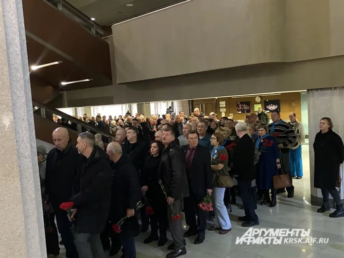 Люди выстроились в очередь, все несут цветы.