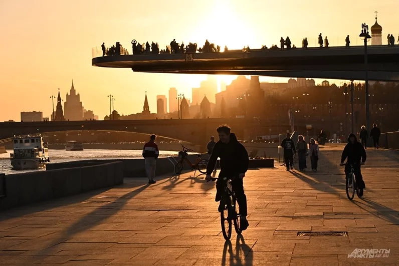 Центр столицы в лучах заходящего солнца: исторические фасады зданий буквально светятся в насыщенном желтом свете вечернего неба.