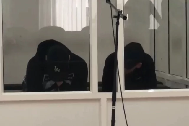 Двое обвиняемых в убийстве на скамье подсудимых.