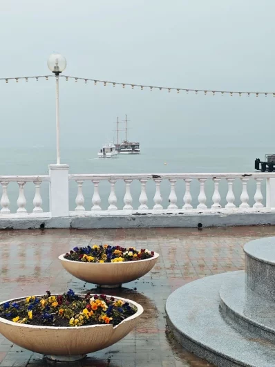 Вдалеке неспешно проплывают яхты и корабли. 