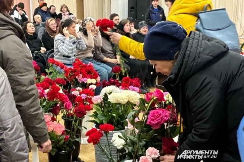 Люди несут цветы в зал прощаний.