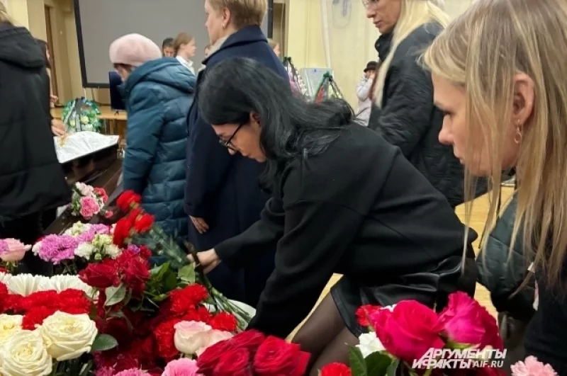 Ученики и их родители несут цветы.