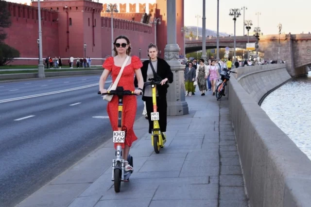 Люди катаются на самокатах в Москве.