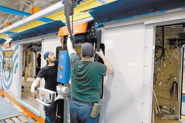 Рабочие Мытищинского завода устанавливают окно на вагон «Москвы-2026».