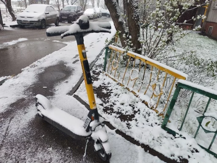 Самокаты, признаки стойкого прихода теплой погоды, теперь выглядят на заснеженных улицах анахронизмом.