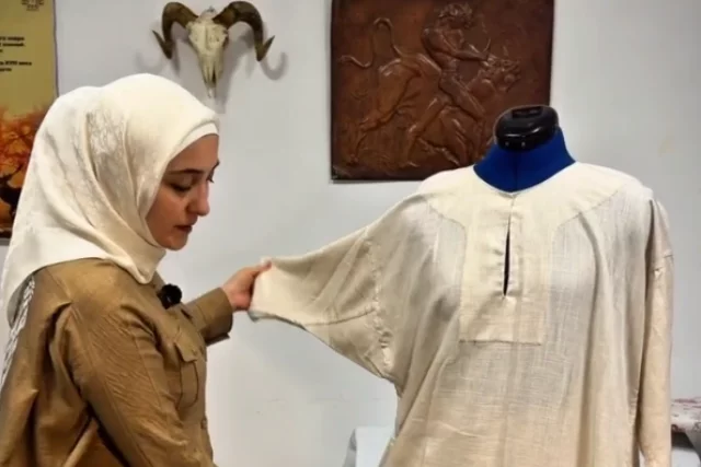 Мастерица заканчивает работу над вторым платьем.