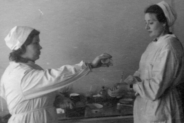 Молодая доктор Дина Романова (слева) в дальневосточной больнице помогает медицинской сестре обработать руки спиртом перед операцией.