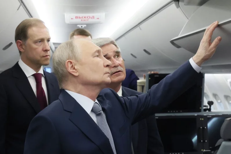 Президент РФ Владимир Путин осматривает салон российского ближнемагистрального пассажирского самолета «Суперджет-100». Слева: первый заместитель председателя правительства РФ Денис Мантуров. 