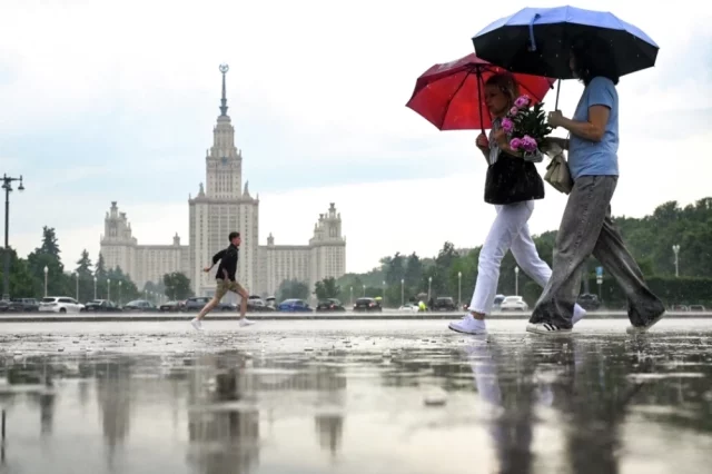 Горожане у МГУ имени М.В. Ломоносова в Москве во время дождя.