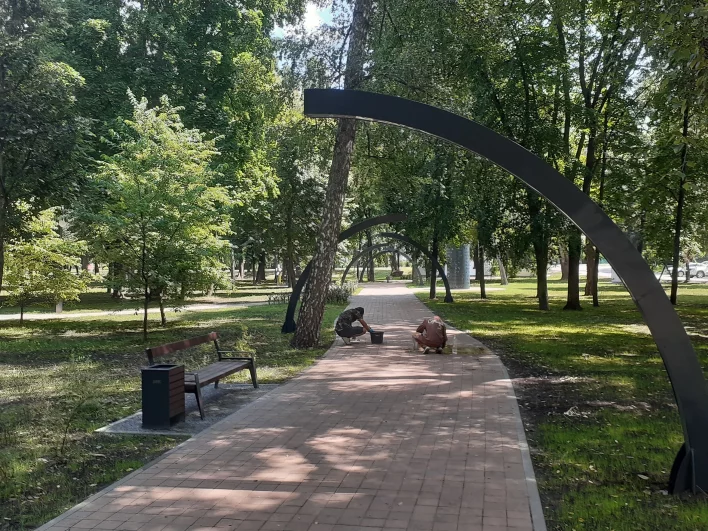 Рабочие чистят дорожки от грязи после дождей.