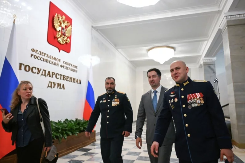 Депутат Государственной Думы РФ, участник специальной военной операции, подполковник, Герой России Энвер Набиев (в центре) и депутат Государственной Думы РФ, участник специальной военной операции, гвардии подполковник медицинской службы Юрий Бровко (справа) перед началом первого пленарного заседания Государственной Думы РФ девятого созыва.