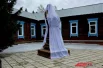 Постамент и бюст стоит на фоне бывшего хирургического корпуса, где оперировал святитель Лука.